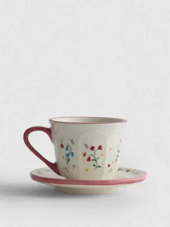 Taza de café con plato y decoración de flores