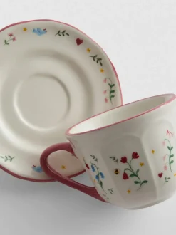 Taza de café con plato y decoración de flores